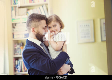 Young father hugging his daughter as he gets home from work Stock Photo