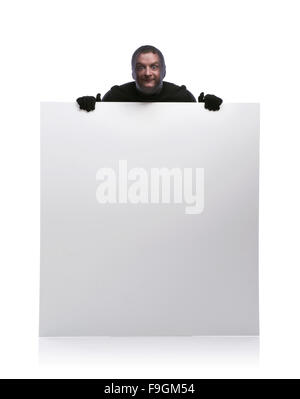 Thief with balaclava on his face, dressed in black, holding an empty banner. Studio shot on white background. Stock Photo