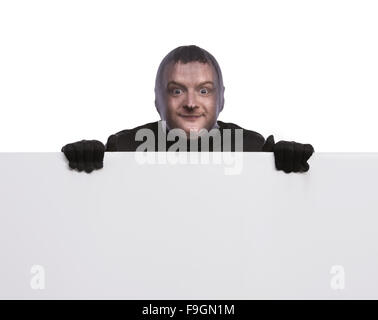 Thief with balaclava on his face, dressed in black, holding an empty banner. Studio shot on white background. Stock Photo