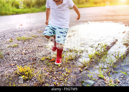 Little boy playing outside in a puddle Stock Photo