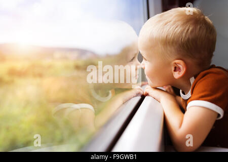 Little boy traveling in train looking outside the window. Stock Photo