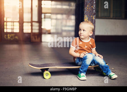 Cute little boy with his skateboard on a walk in the city Stock Photo