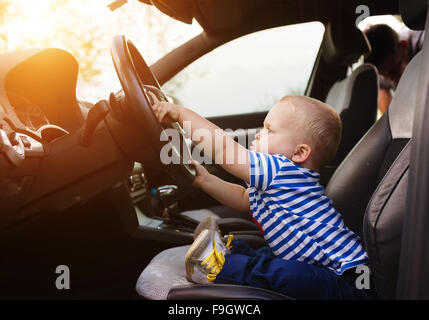 Little boy playing with a steering wheel in a car Stock Photo