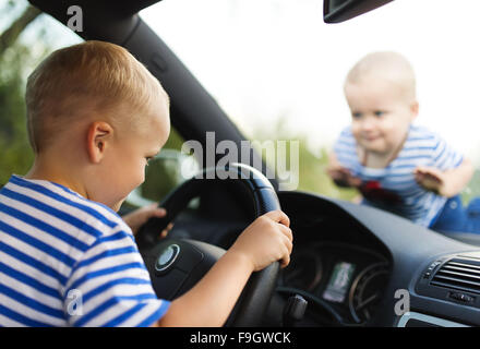 Little boy playing with a steering wheel in a car Stock Photo