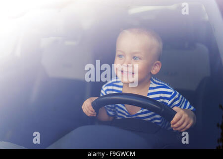 Little boy playing with a steering wheel in a car Stock Photo