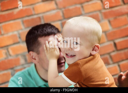 Father and son making funny faces together on a brick wall background Stock Photo