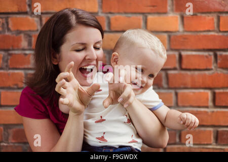 Mother and son making funny faces together on a brick wall background Stock Photo