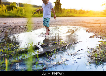 Little boy playing outside in a puddle Stock Photo