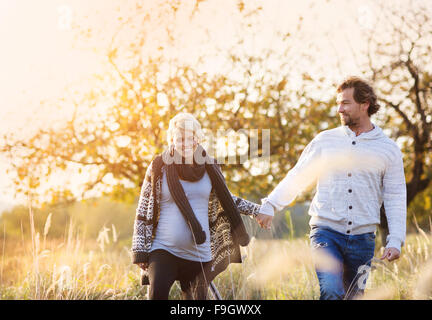 Happy young pregnant couple spending time together outside in green nature. Stock Photo