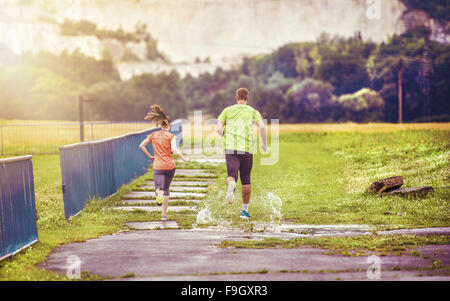 Young couple jogging on asphalt in rainy weather Stock Photo