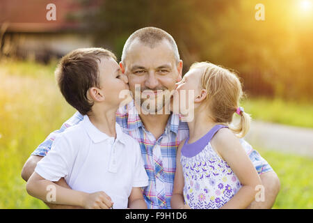 Father with his two children spending time together outside in green nature. Stock Photo