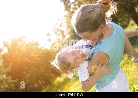 Happy little girl having fun with her mother in green nature. Stock Photo