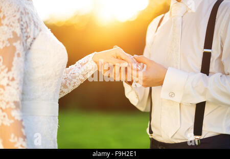 Young wedding couple holding hands as they enjoy romantic moments outside on a summer meadow Stock Photo