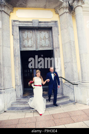 Bride and groom walking out of the church holding hands Stock Photo