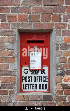 The Ludlow wallbox. A traditional British wall mounted red letterbox from the reign of George V. Moreton village, Dorset, England, United Kingdom. Stock Photo