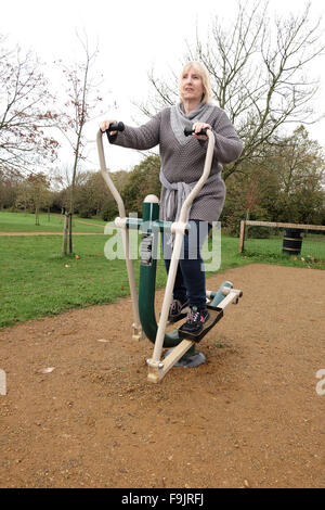 Mature woman on an exercise machine in the public park, Swanley, Kent, UK. Stock Photo