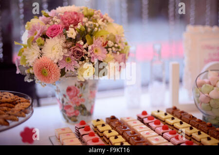 Beautiful bouquet in vase with colorful flowers and sweets on table Stock Photo