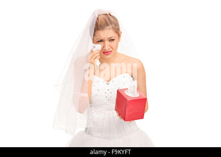 Young bride in a wedding dress crying and wiping her tears isolated on white background Stock Photo