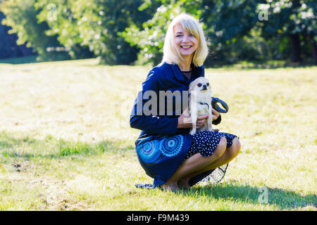 Pretty blonde lady holding her scared chihuahua Stock Photo