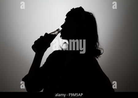Dark profile silhouette of woman drinking from bottle Stock Photo