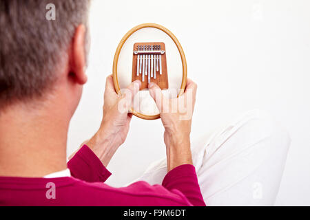 Relaxed man playing on a version of the African instrument Kalimba Stock Photo