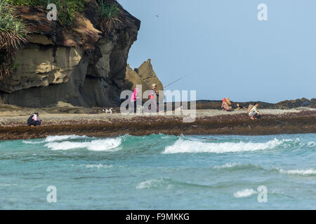 Anglers fishing from rocks on Tip of Borneo beach Sabah East Malaysia Island of Borneo Stock Photo