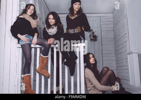 Four stylish models posing sitting on the fence Stock Photo