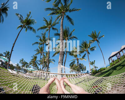 A wide angle fisheye view of a young couple's feet in a hammock on the grounds of the Fairmont Orchid, Kohala Coast, Hawai'i. Stock Photo