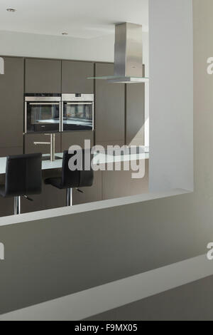 A modern family house, a kitchen showing double oven and hob. Two chairs and a kitchen island. Stock Photo