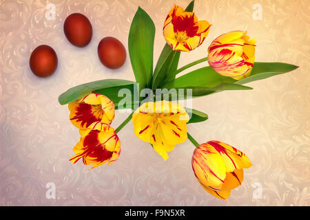 Beautiful yellow and red tulips , and near them three red Easter eggs. The view from the top. Stock Photo