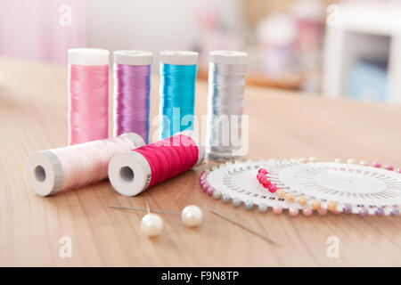 Sewing thread in different colors with pins on a table Stock Photo