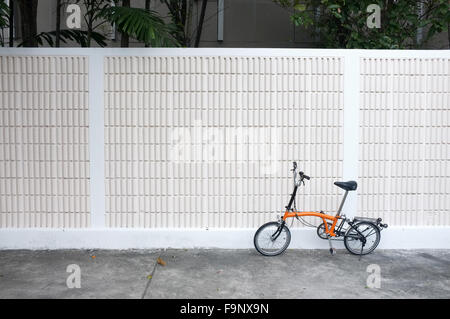 Orange bicycle parks in front of wall Stock Photo