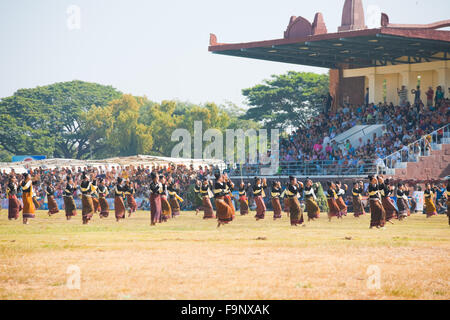 Many traditionally dressed women performing dance in front of audience on field at the annual Surin Elephant Roundup Festival Stock Photo