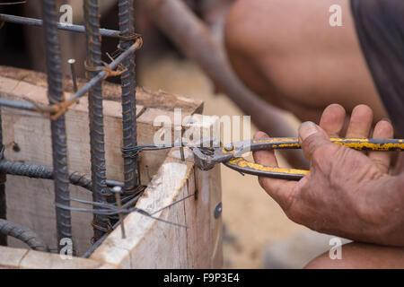 Close up of construction worker hands working with pincers on fixing steel rebar at building site Stock Photo