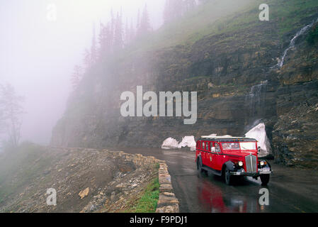 Glacier National Park, Montana, USA - Red Jammer Tour Bus driving Sightseeing Tourists along Going to the Sun Mountain Road Stock Photo