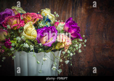 vintage colorful preserved roses on dark tone wooden background Stock Photo
