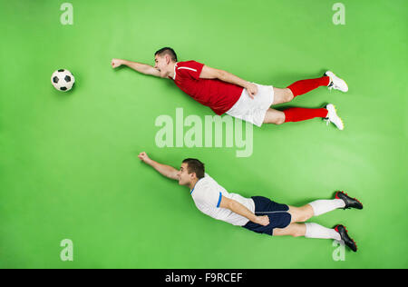 Two football players in a superman pose. Studio shot on a green backroung. Stock Photo