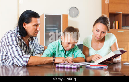 Teenager schoolboy doing homework with parents Stock Photo