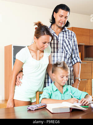 teenager schoolboy doing homework against cheerful parents Stock Photo