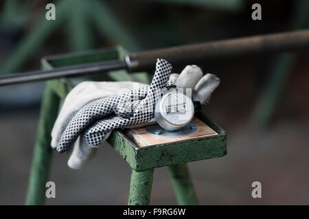 Protective gloves and a mechanical counter on a workbench at a glass blowing manufacture / glass furnace Stock Photo