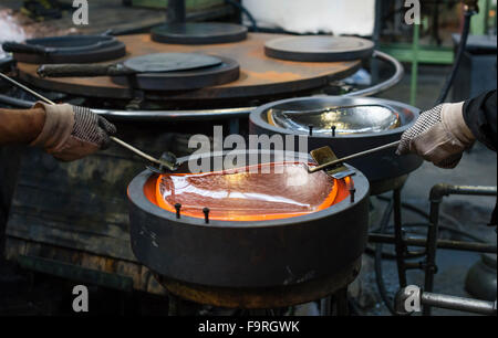 Melted glass, glowing red hot, being shaped in a mould at the traditional glassblowing manufacture at Hergiswil, Switzerland. Stock Photo