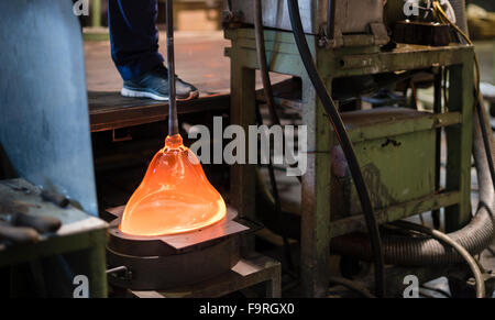 Melted glass, glowing red hot, is being shaped in a mould at the traditional glassblowing manufacture at Hergiswil, Switzerland. Stock Photo
