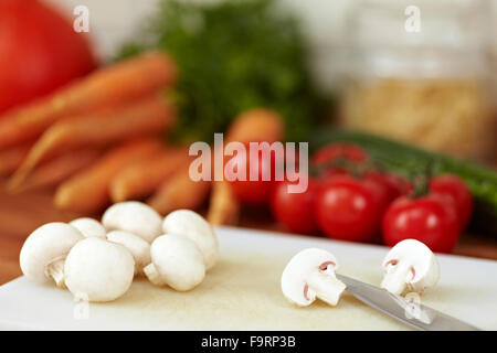 Cutting cultivated white mushrooms into halves with a knife Stock Photo