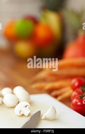 Knife on a kitchen counter cutting White Mushrooms in half Stock Photo