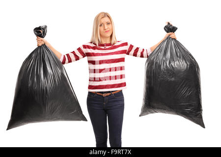 Displeased young woman holding two black trash bags and looking at the camera isolated on white background Stock Photo