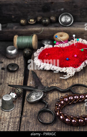 Scissors,thread,buttons and needles on wooden vintage background. Stock Photo