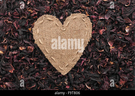 Frame in the shape of heart made of burlap with dried hibiscus, with space for your text Stock Photo