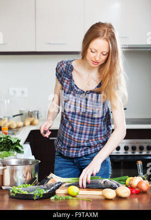 Long-haired woman cooking  fish   at home kitchen Stock Photo