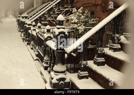 Snow covered Brooklyn brownstone townhouse stoops and sidewalk in winter. Retro sepia tone for vintage effect. Stock Photo