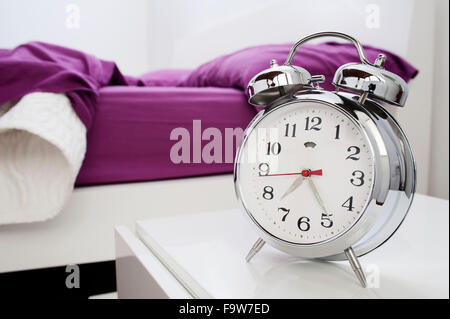 classical alarm clock on bedside table Stock Photo